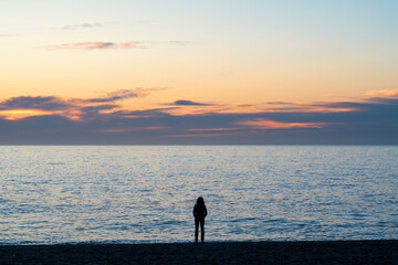 Silueta de mujer joven al amanecer el la orilla de la playa de Granada, España