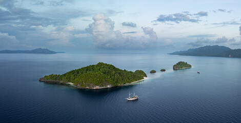 Dawn illuminates scenic limestone islands fringed by beautiful coral reefs in Raja Ampat,...