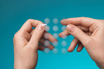 Close-up round acne patch on finger on blue background. Acne patches for treatment of pimple and...