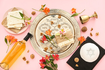 Composition with Passover Seder plate, flatbread matza, bottle of wine, Torah and flowers on pink background