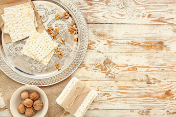 Passover Seder plate with flatbread matza and walnuts on light wooden background