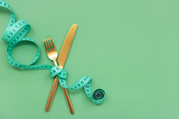 Measuring tape and cutlery on green background. Diet concept