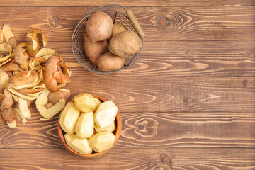 Bowl and basket with raw potatoes on wooden background