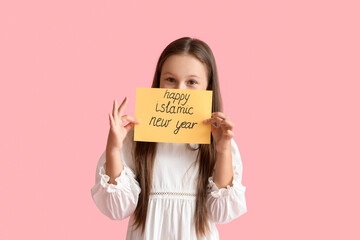 Little Muslim girl with greeting card for Islamic New Year on pink background