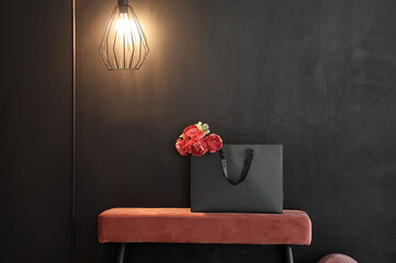 Shopping bag with flowers on pink bench in stylish room