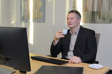 employee takes coffee break sitting at his computer