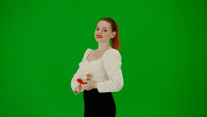 Portrait of attractive office girl on chroma key green screen. Woman in skirt and blouse holding mirror, brush and smiling.