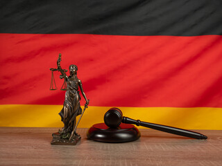 Bronze statue of justice and judge's gavel against the background of the German flag. Law and...