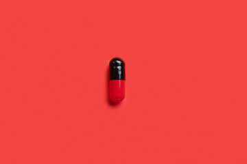 Medical capsule on red background - obrazy, fototapety, plakaty