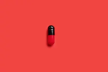 Zelfklevend Fotobehang Medical capsule on red background © Pixel-Shot