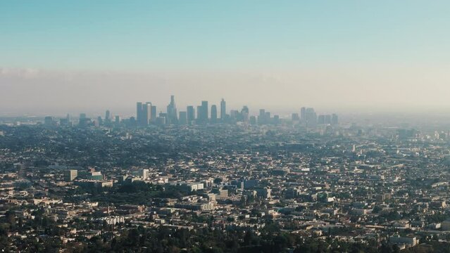 Aerial footage over hills and mountains and view of Los Angeles, California on sunny day