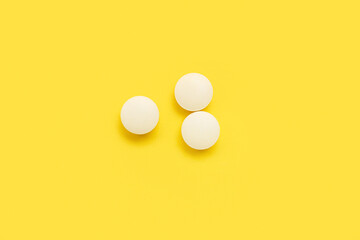 White medical pills on yellow background