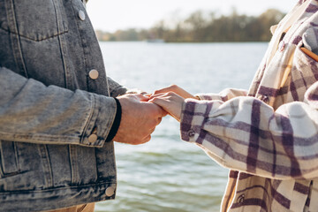 Cropped image hands young loving couple standing outside beach shore in sunny weather, hugging...