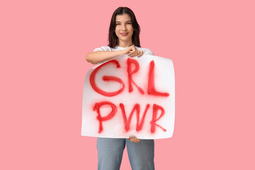 Young woman with sign GRL PWR on pink background. Feminism concept
