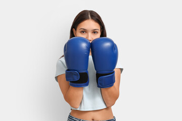 Young woman in boxing gloves on white background. Feminism concept