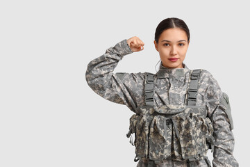 Young female soldier flexing muscles on white background. Feminism concept