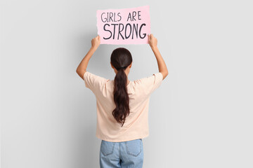 Young woman with sign GIRLS ARE STRONG on white background, back view. Feminism concept