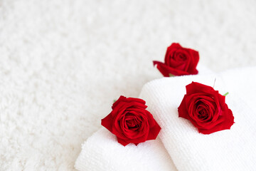 Obraz na płótnie Canvas White towels with red roses. Spa and wellness or beauty salon, romantic relaxation concept. Valentine's Day. Copy space.