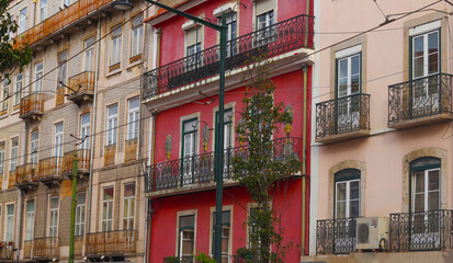Fototapeta na wymiar Exterior facades of historical houses with apartments in Lisbon, Portugal. Urban vintage background. Alfama district. The building is tiled with carved balconies.