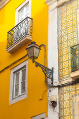 Exterior facade of yellow historical house with apartments in Lisbon, Portugal. Urban vintage background. Alfama district. The building is tiled with carved balconies. - obrazy, fototapety, plakaty