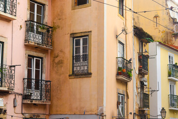 Fototapeta na wymiar Exterior facade of historical houses with apartments in Lisbon, Portugal. Urban vintage background. Alfama district. The building is tiled with carved balconies.