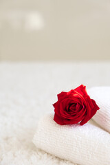 White towels with red rose on white background. Spa therapy, massage salon, romantic relaxation concept. Love, care, romance, treatment. Selflove. Copy space.
