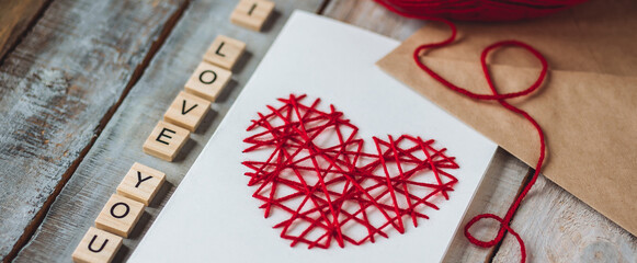 Concept of creative handmade postcard, greetings, romantic notes for Saint Valentine's Day. Words I love you written in wooden letters, craft envelope, do it yourself card with red heart banner