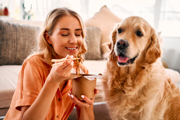 Cozy domestic moment. Golden retriever with eager anticipation sitting on floor near female owner...