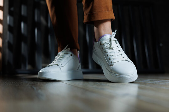 Comfortable women's sneakers on a flat sole with laces. Close-up of female legs in white perforated leather sneakers. Women's summer sneakers. Collection of women's leather shoes © Дмитрий Ткачук