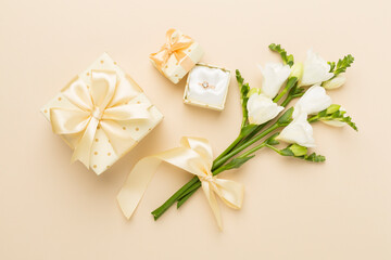 Fototapeta na wymiar White fresia flower and gift box with diamond ring on color background, top view