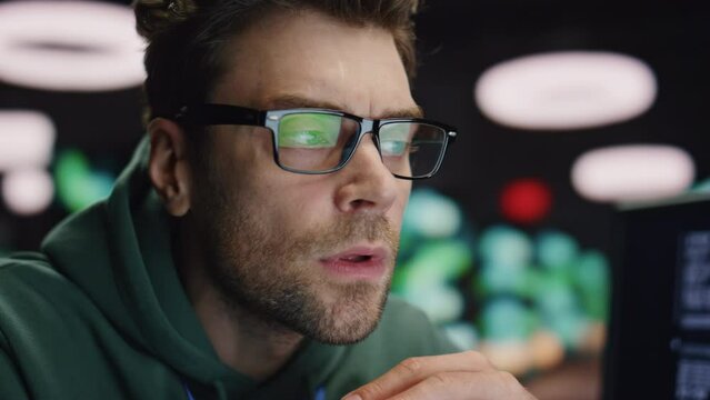 Closeup serious developer working at night datacenter. Tired man found mistake