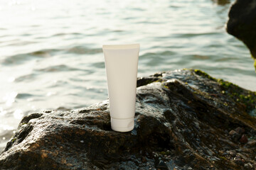 White tube of moisturizing cream or lotion for body and face on a wet stone on a background of the...