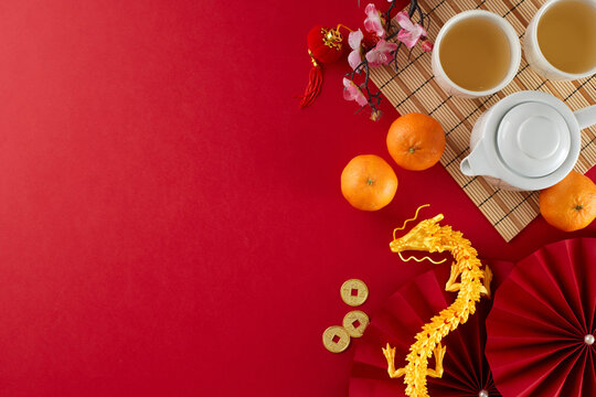 Engaging in the chinese New Year tea ceremony tradition. Top view photo of teapot, cups of tea, tangerines, gold dragon, decorative elements on red background with promo area - Powered by Adobe