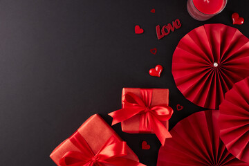 Choice of gifts for Valentine's Day concept. Top view shot of red gift boxes, folding fans, candle, hearts on black background with promotional slot