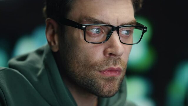 Closeup man coder working night datacenter. Serious developer looking computer