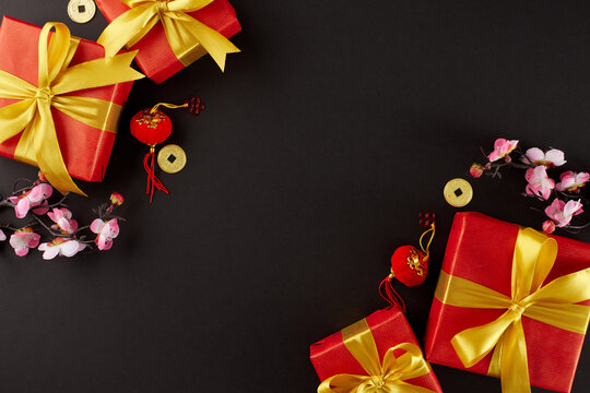 Celebratory gifts for the Year of the Dragon. Top view shot of elegant gift boxes, sakura, lucky coins, lanterns on black background with ad space - Powered by Adobe