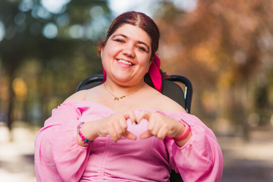 InspireInclusion heart shape, love valentine gesture. Young woman with cerebral palsy disability. 