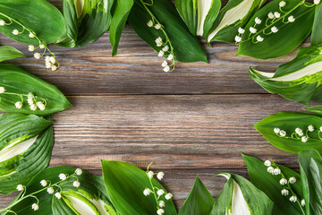 Flower composition. Frame made of lily of the valley flowers on rustic wooden background. Flat lay....