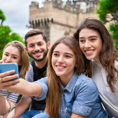 Eine Gruppe junger Menschen macht ein Selfie mit einer Burg im Hintergrund