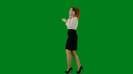 Portrait of attractive office girl on chroma key green screen. Woman in skirt and blouse walking talking on smartphone, positive face expression. Side view.