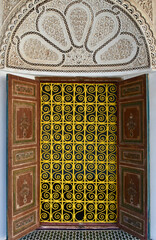 Moroccan Palace Window with Decorative Yellow Grate, Wooden Shutters, and Arched Alcove