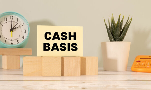 The word cash basis written on a notepaper on business office desktop. Accounting method that recognizes revenues