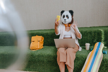 Businesswoman in mask of panda working in the lounge zone in office