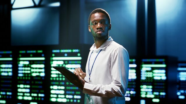 Computer scientist using tablet to check server room security features protecting against unauthorized access, data breaches, distributed denial of service attacks and other cybersecurity threats