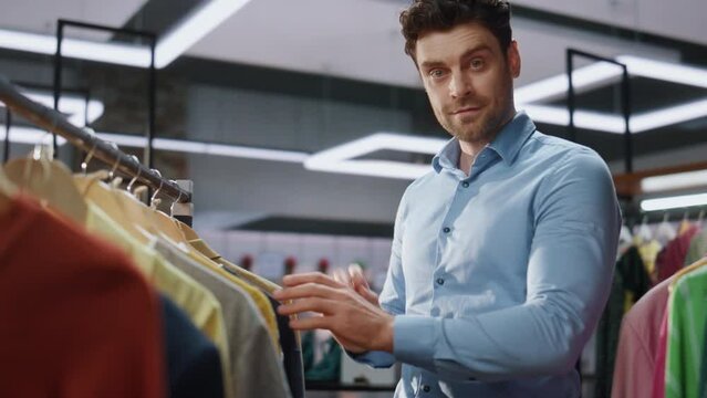 Store worker looking clothes at boutique closeup. Man posing camera portrait 