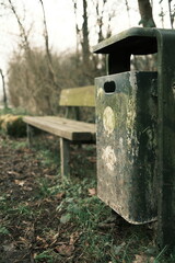 Green trash can next to a park bench in Meerbusch, Germany