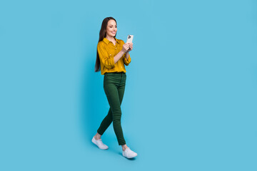 Fototapeta na wymiar Full length photo of funky excited lady wear yellow shirt texting instagram twitter telegram facebook empty space isolated blue color background
