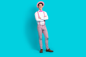 Full length photo of optimistic man dressed pink retro cap pants on suspenders hold arms crossed isolated on blue color background