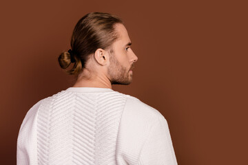 Photo of positive attractive man wear white sweater standing back looking empty space isolated brown color background