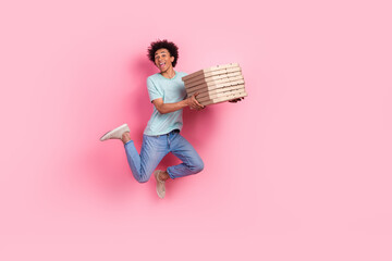 Full body photo of attractive young man jump running deliver pizza boxes dressed stylish blue clothes isolated on pink color background